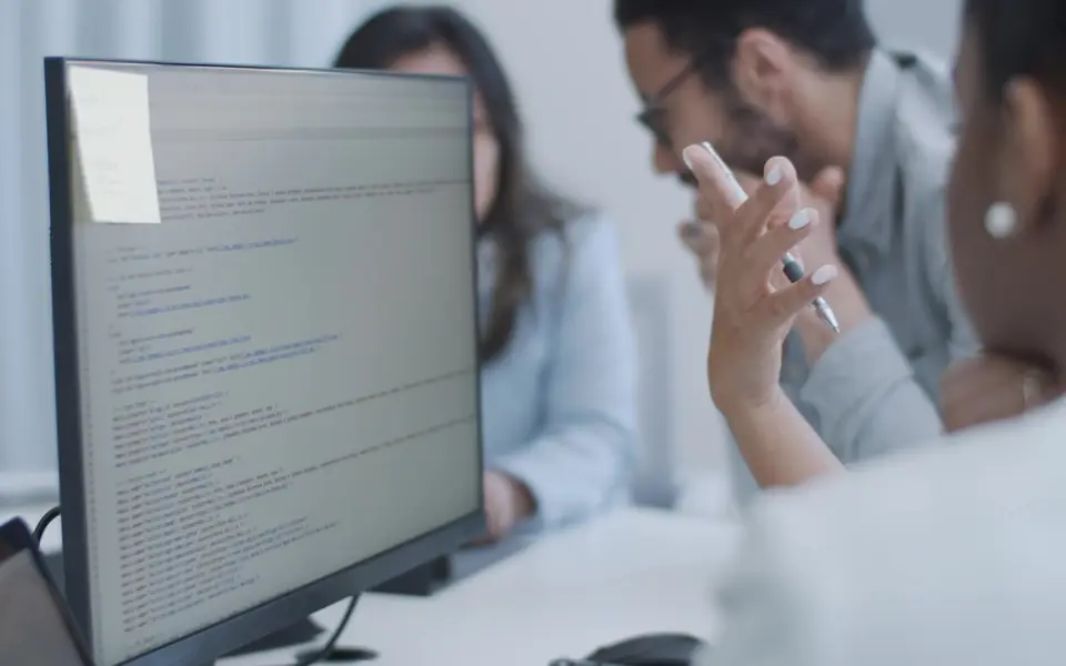 Two people at a monitor of code