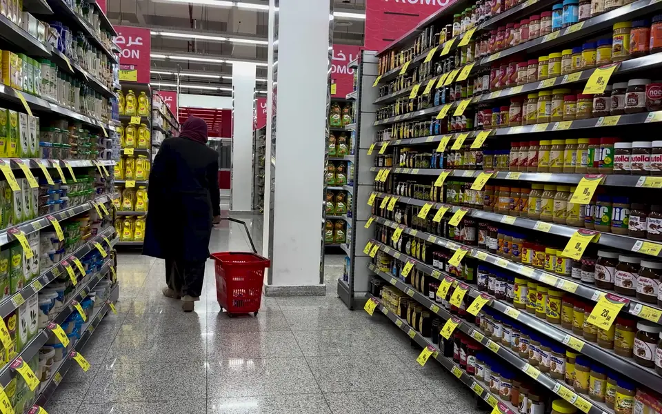 A shopper with a basket in a supermarket aisle