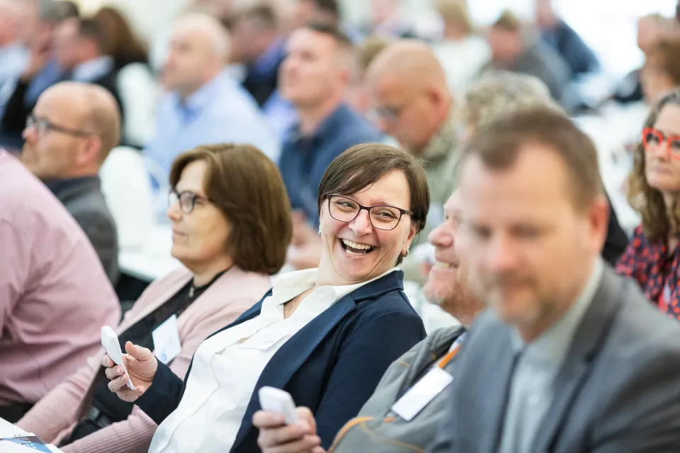 A conference audience, several people holding small voting keypads